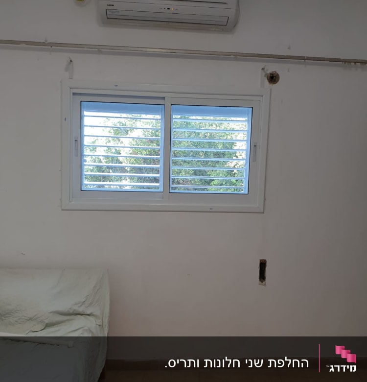 חלון עם תריסי אלומיניום על קיר לבן